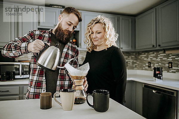 Mann gießt heißes Wasser in den Kaffee  den er übergießt  während die Frau zuschaut