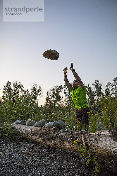 Starker Mann wirft während eines Trainings im Freien große Steine.