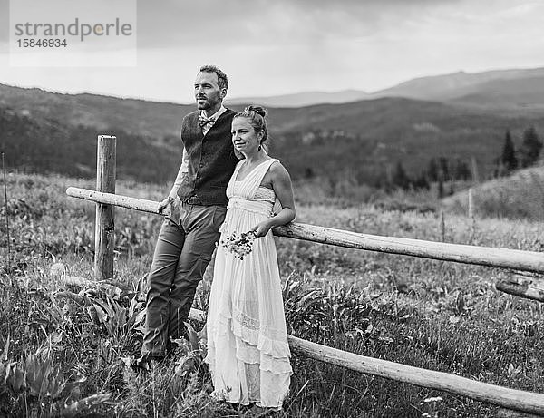 Schwarzweiß von Braut und Bräutigam an den Zaun gelehnt in Wyoming
