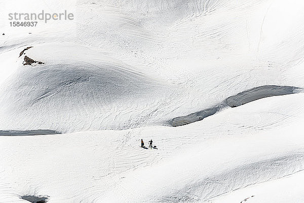 Zwei nicht erkennbare Personen in verschneiten Bergen beim Wintersport