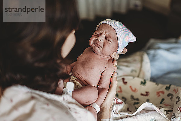 Neugeborener Junge mit Hut im Krankenhaus macht komisches Gesicht