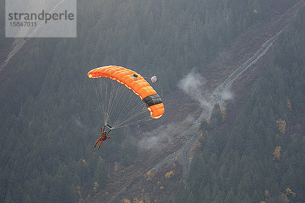 Ein Fallschirmjäger der Canada Search and Rescue fliegt umgeben von Bergen ein und landet während eines Trainingseinsatzes auf dem Gras am Flughafen Pemberton.