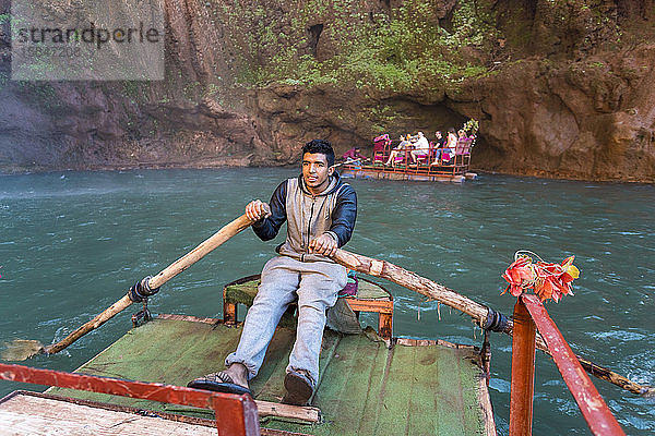 Ein Marokkaner paddelt auf einem Touristenboot bei Ouzoud