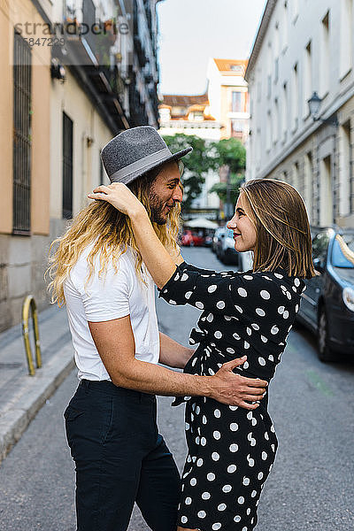 Glückliches stilvolles Paar  das sich in formaler Kleidung auf der Straße umarmt