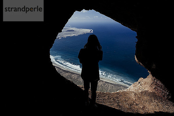 Silhouette eines Mannes aus einer Höhle in den Klippen von Famara auf Lanzarote