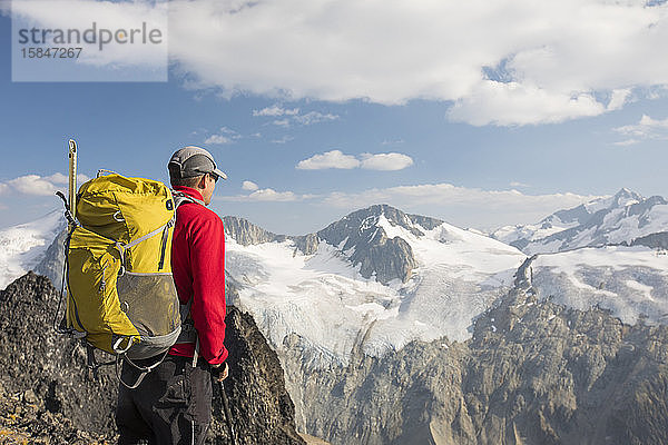 Seitenansicht eines Rucksacktouristen in den Bergen mit Blick auf Gletscher.