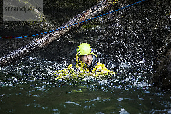 Mann schwimmt durch einen Pool  nachdem er sich in einer Flussschlucht abgeseilt hat