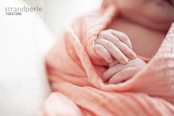 Nahaufnahme der Hände neugeborener Mädchen in rosa Decke gewickelt