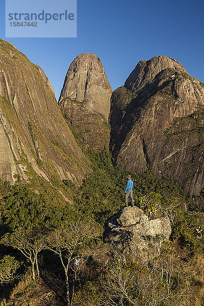Mann posiert in der Nähe dramatischer felsiger Berggipfel im Regenwald
