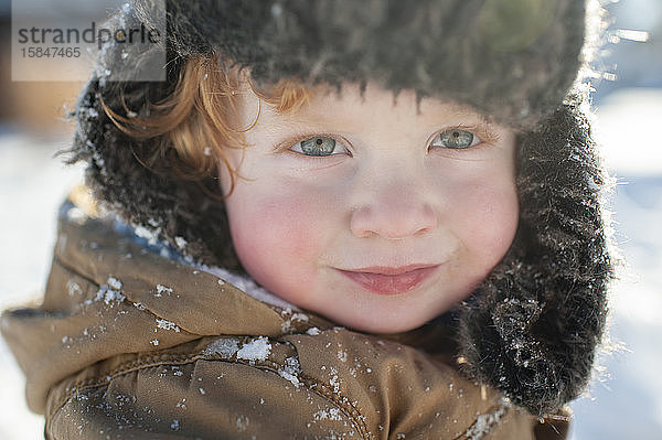 Porträt eines glücklich lächelnden Kleinkindes mit Winterhut in Jacke