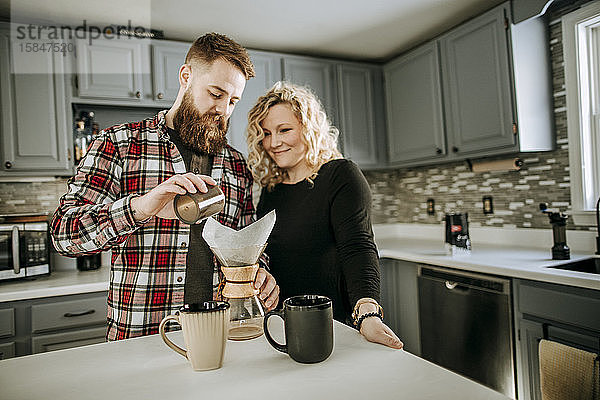 Mann mit Bart und Frau kochen gemeinsam in ihrer Küche Kaffee
