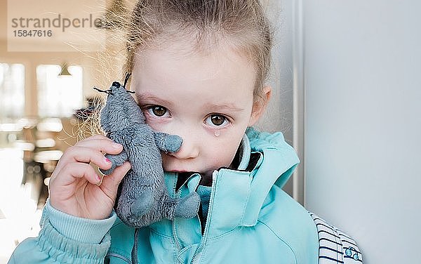 Junges Schulmädchen weint und hält ihr Spielzeug traurig