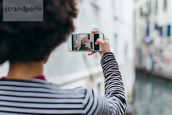 Junge Frau beim Fotografieren mit einem Mobiltelefon