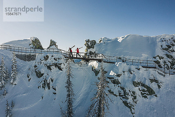 Mit einer Drohne fotografierte Skifahrer beim Wandern auf Gipfeln