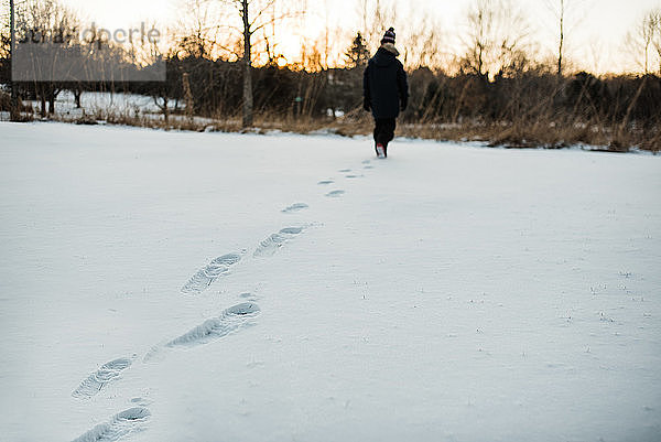 Blick auf die Fußabdrücke eines Jungen im Schnee während des Winters in Minnesota.