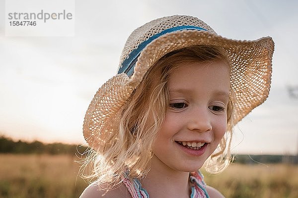 Nahaufnahme des Porträts eines Mädchens  das bei Sonnenuntergang lächelt  während es draußen spielt