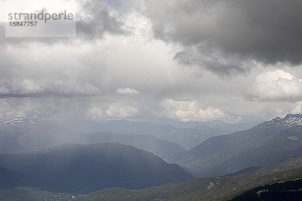 Wenn man an einem Frühlingstag von der Bergspitze auf das Whistler Valley blickt  sieht man in der Ferne einen Regensturm.