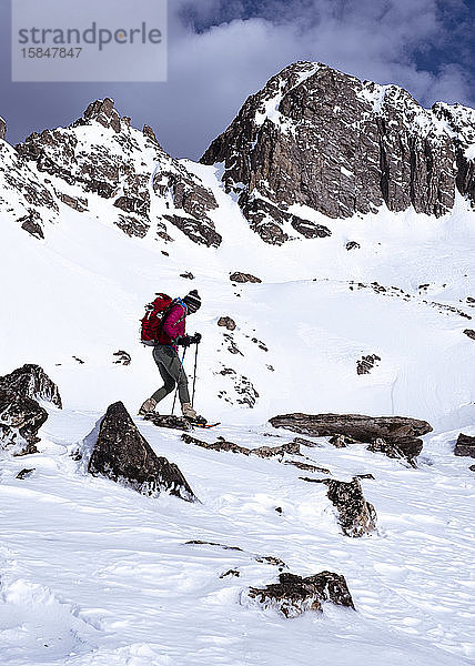 Frau beim Schneeschuhwandern in schneebedeckten Bergen im Winter in Montana