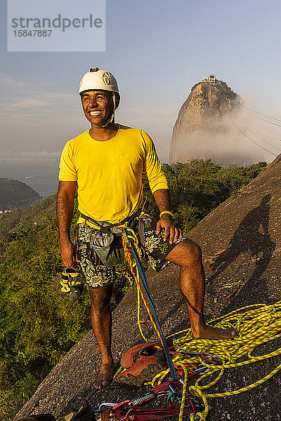 Bergsteiger lächelt mit dem Zuckerhut auf dem Rücken