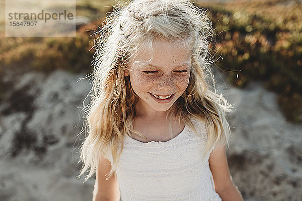 Porträt eines jungen Mädchens im Schulalter mit Sommersprossen  das am Strand wegschaut