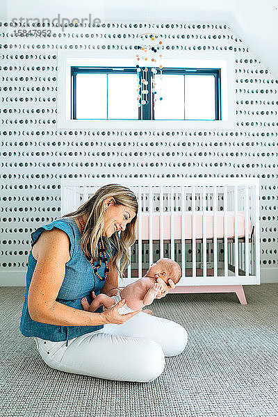 Eine Mutter hält ihr Neugeborenes in einem modernen Kinderzimmer