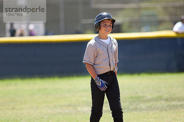 Kleiner Ligaspieler mit Baseballhelm lächelt