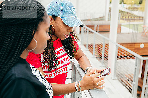 Freunde unterhalten sich im Freien mit Blick auf das Smartphone