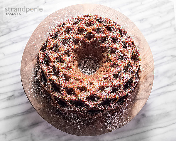 Haselnuss-Jubiläumsbundtorte auf Walnuss-Stand vor Marmor-Hintergrund