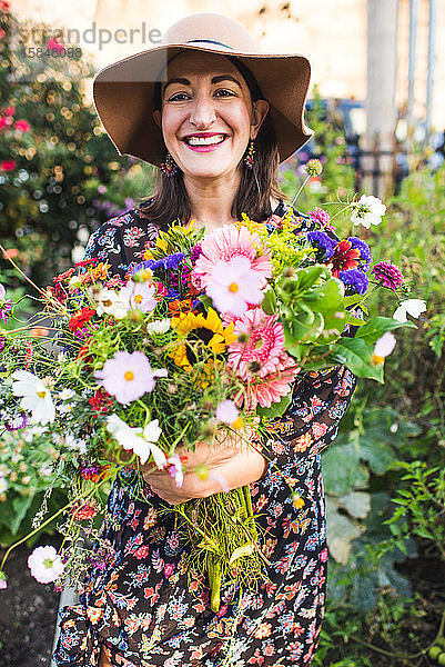 glücklich lächelnde Frau im Garten mit Blumen