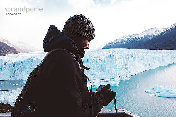 Männlicher Reisender überprüft seine Kamera in Gletschernähe an bewölktem Tag
