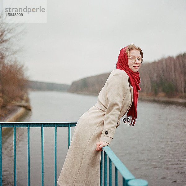 Eine Frau steht mit einem roten Schal am Flussufer