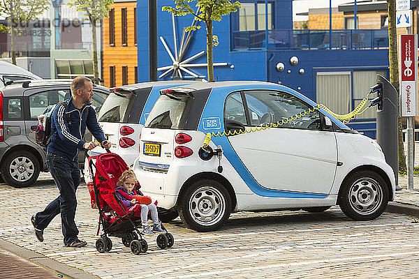 Ein Elektroauto vom Typ Smart an einer Ladestation für Elektroautos in Ijburg  Amsterdam  Niederlande  vor schwimmenden Häusern.