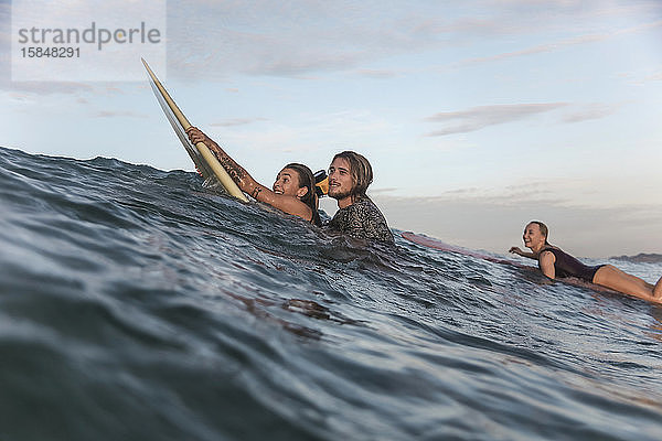 Glückliche Freunde mit Surfbrettern im Meer