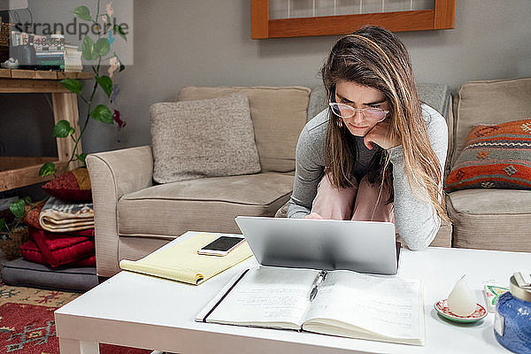 Junge Frau arbeitet während COVID von zu Hause am Laptop