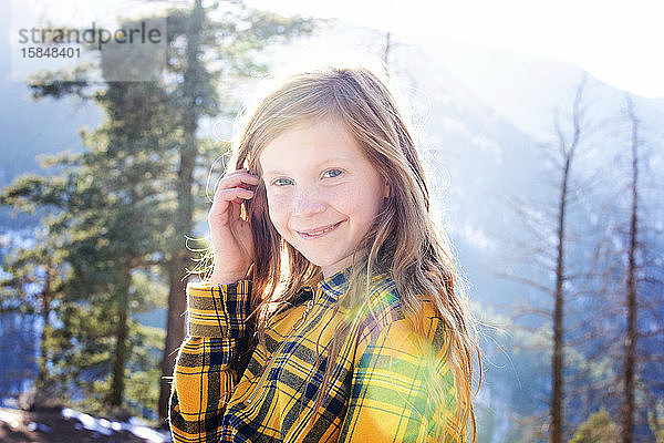 Schönes junges Mädchen mit rotem Kopf an einem sonnigen Tag in den Bergen im Freien