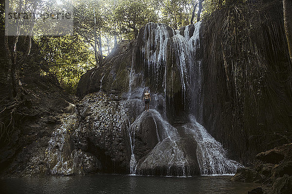 Junger Mann klettert auf Wasserfall