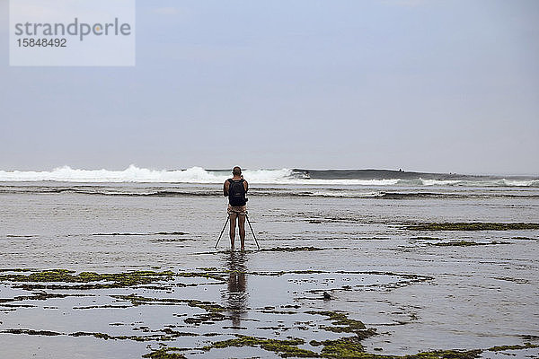 Fotograf mit Stativ beim Fotografieren eines Surfers