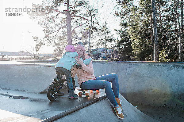 Umarmung der Mutter und ihrer Tochter beim Spielen in einem Skatepark
