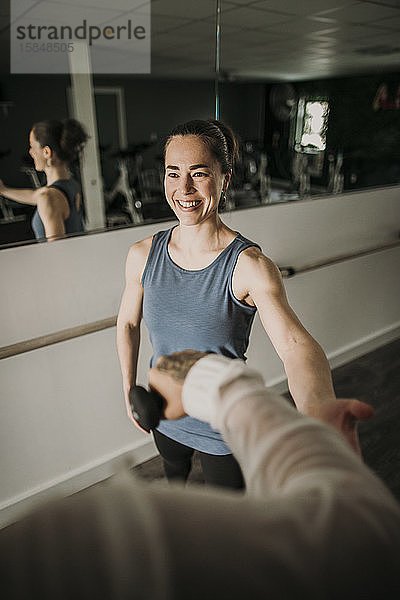 Lächelnde weibliche Personal Trainerin coacht eine Person beim Gewichtheben