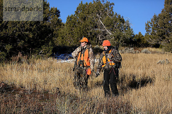 Zwei Jägerinnen wandern auf einer Wiese in Colorado