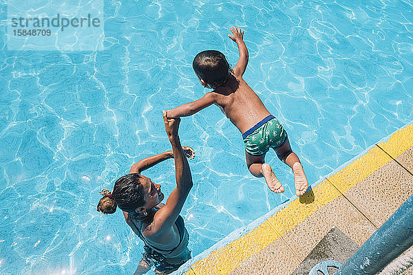 Eine Frau hilft einem Kind  in einen Pool zu springen