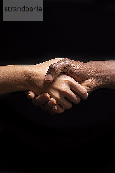 Händeschütteln von Männern und Frauen mit unterschiedlichen Hauttönen