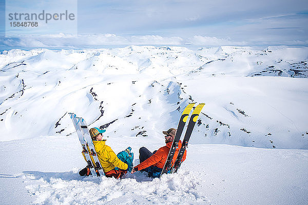 Ein Mann und eine Frau entspannen sich mit Skiern vor der Bergkulisse