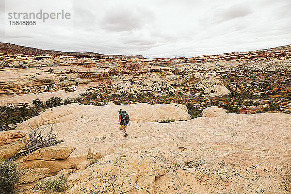 Rucksacktouristin geht eine Sandsteinfelswand in der Wüste von Utah hinunter