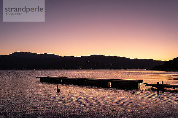 ein Sonnenuntergang über einem Dock mit Bergen