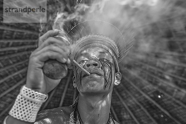 Brasilianischer Indianer raucht traditionelle Pfeife im Dorf