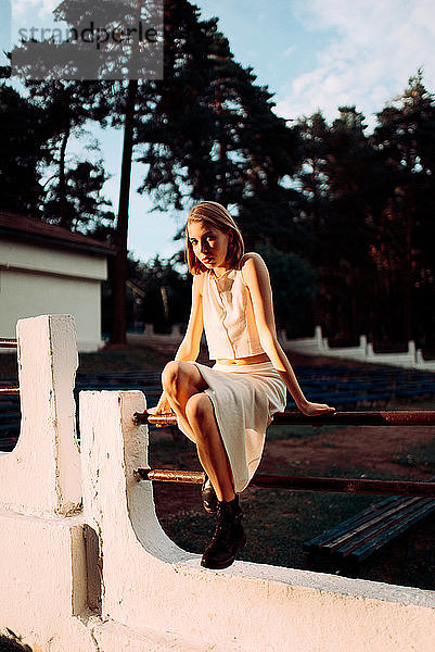 Junge Frau sitzt auf dem Zaun