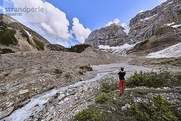 Eine Frau hält an  um ein Foto des Gletscherabflusses über dem Cirque Lake zu machen.