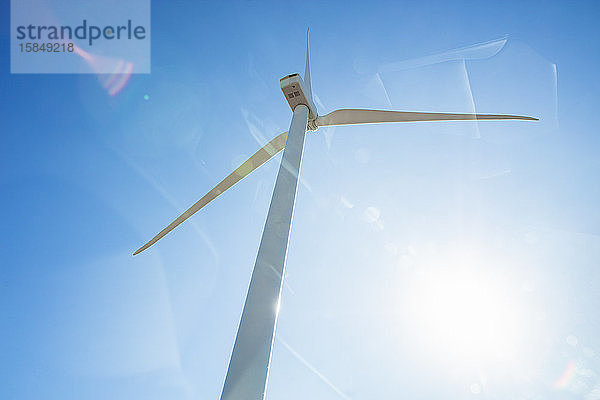 Aufblick zur Windkraftanlage gegen blauen Himmel mit Sonneneruption