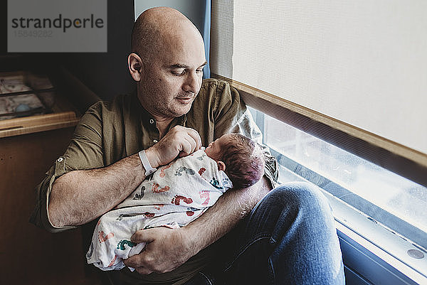 Vater hält neugeborenen Jungen in Decken eingewickelt im Krankenhaus